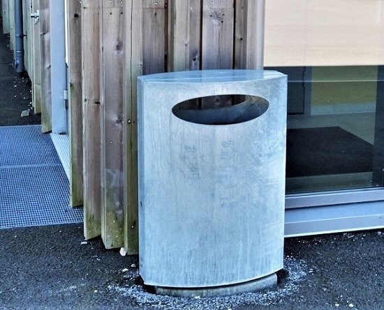 Søppelkasse plassert rett ved trevegg