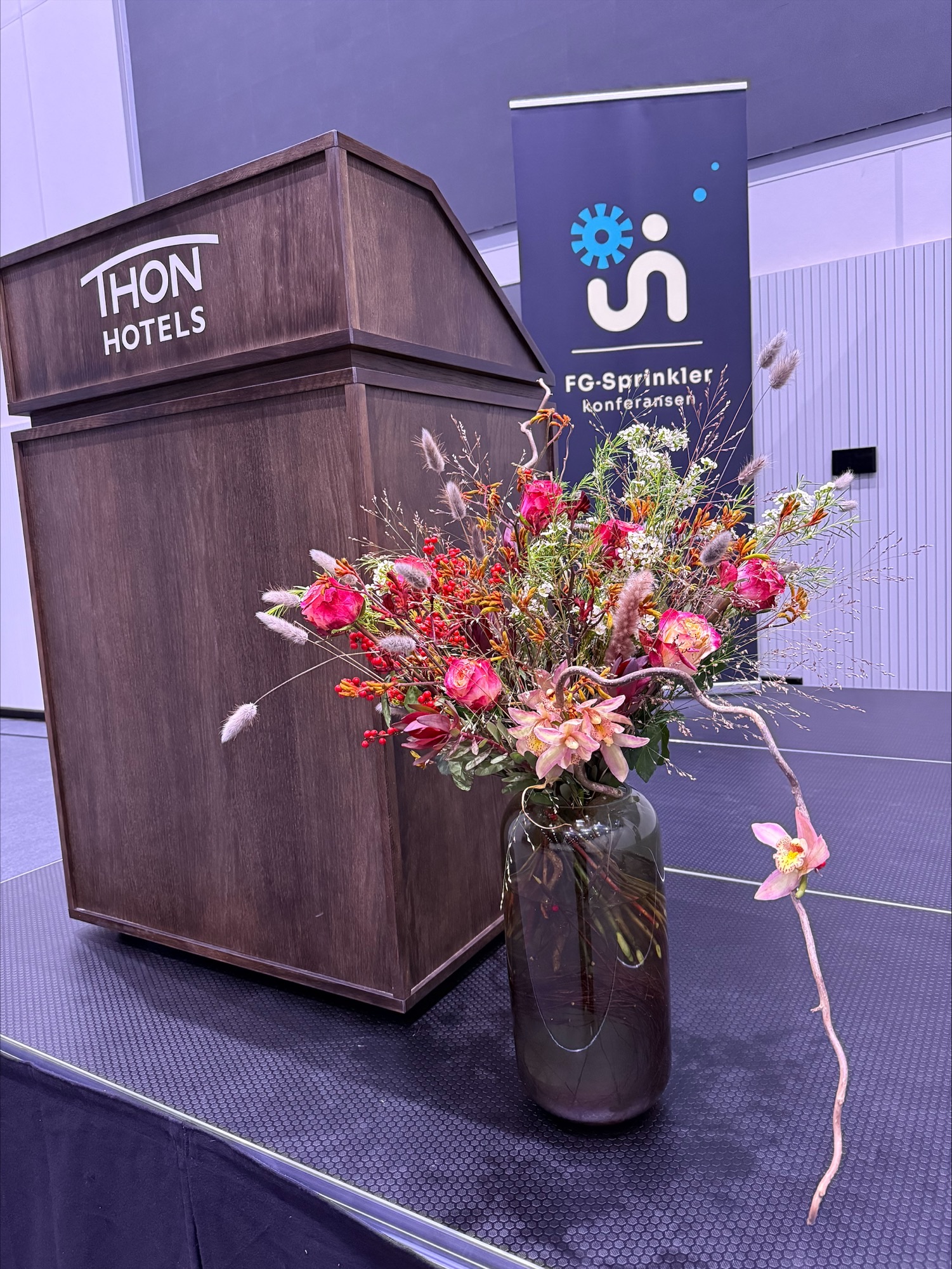 Bilde av en scene med talerstol og blomsterdekrasjoner